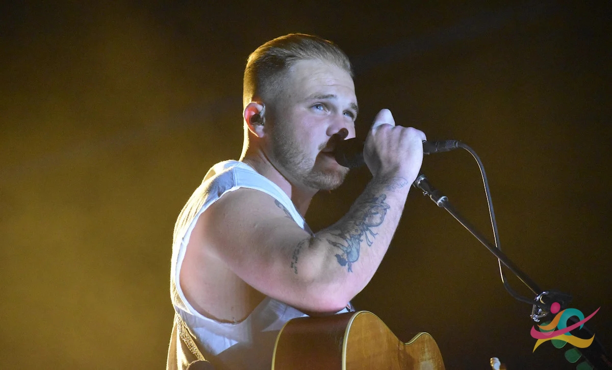 zach bryan singing a song in stage with the help of mic